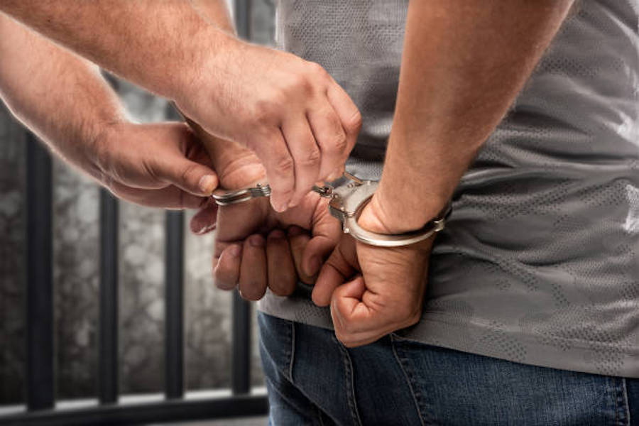 Criminal Handcuffed In Front Of Prison Bars